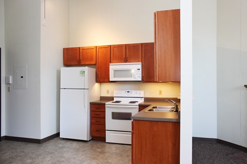 A kitchen with white appliances and wooden cabinets.