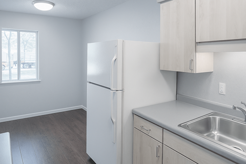 A kitchen with a white refrigerator, sink, and cabinets.