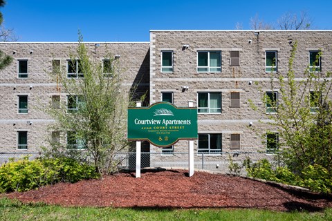 A sign in front of a building that says Courtview Apartments.
