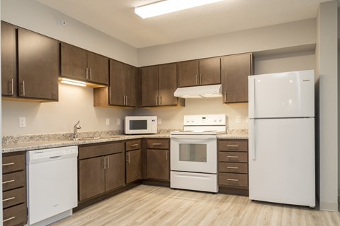 A kitchen with white appliances and brown cabinets.