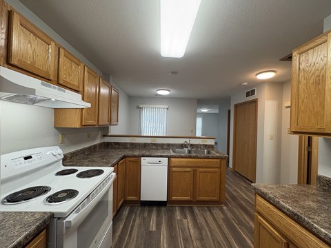 A kitchen with a white stove top oven and a white dishwasher.
