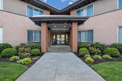 A building entrance with a concrete pathway and a brick pillar.