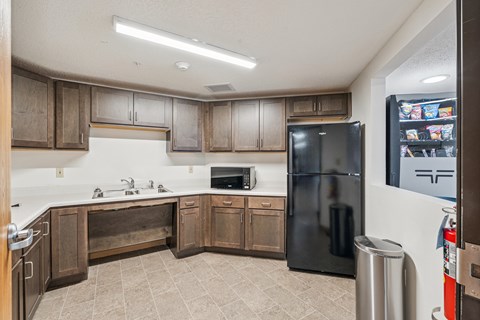 A kitchen with a black refrigerator and wooden cabinets.