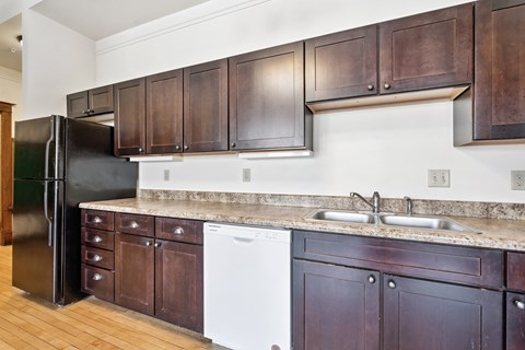 A kitchen with dark wood cabinets and a black refrigerator.