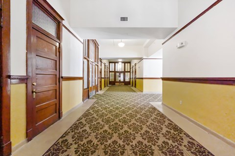 A hallway with a patterned carpet and wooden doors.