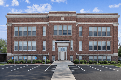 A large red brick building with a white door and windows.