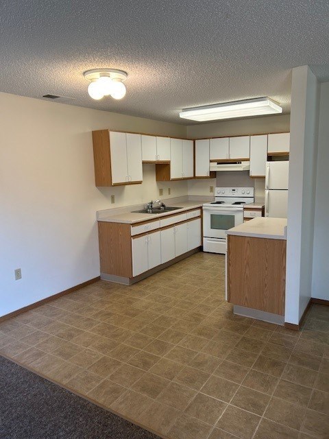 A kitchen with white appliances and wooden cabinets.