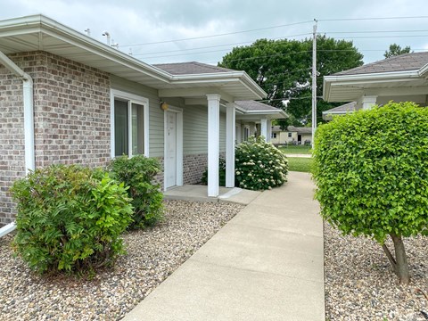 A residential area with a house, bushes, and a gravel path.