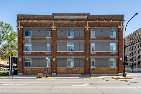 A large brick building with many windows is on a street corner.