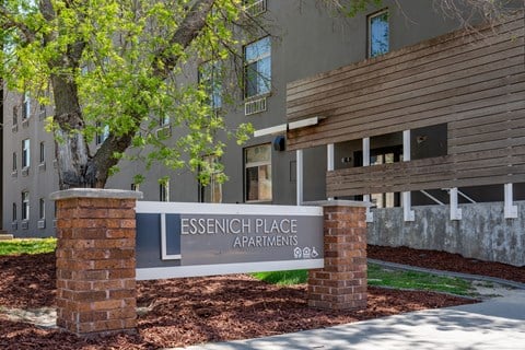 A sign for Essenich Place Apartments stands in front of a building.
