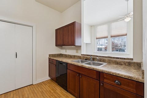A kitchen with brown cabinets and a black dishwasher.