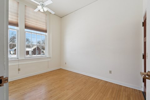 A room with a ceiling fan and a window with blinds.
