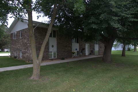 A small building with a white roof and a tree in front of it.