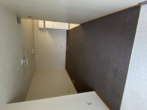 A white laptop is on a white desk in a room with a brown wall.