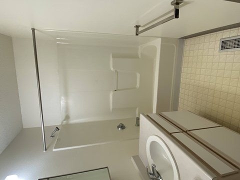 A white bathroom with a glass shower door and a white toilet.