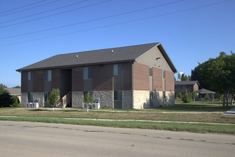 A large brick building with a grey roof and a small porch.