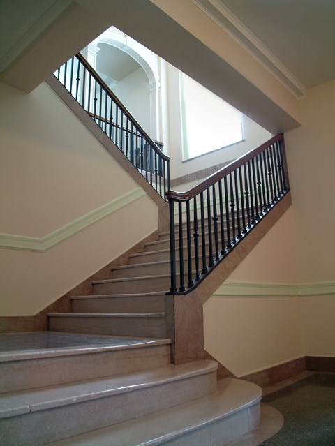 A staircase with a black railing and beige steps.