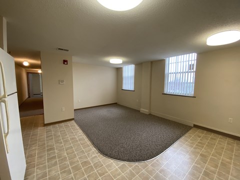 A spacious room with a carpeted area in the center and a door to the left.