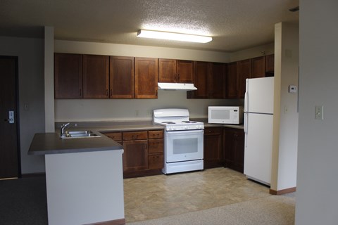A kitchen with white appliances and brown cabinets.