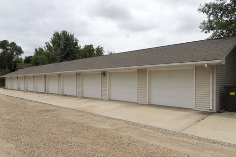 A long building with a grey roof and white garage doors.