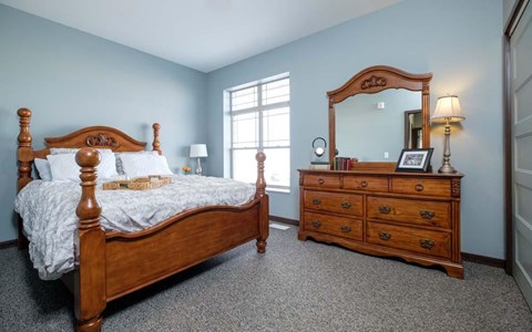 A bedroom with a bed, dresser, and mirror.