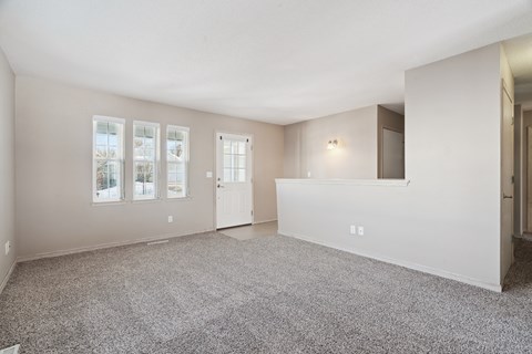 A spacious room with carpeted floor and a large window.