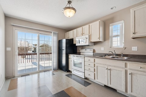 A kitchen with a black refrigerator and white cabinets.