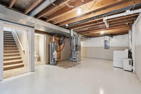 A room with a staircase and a furnace.