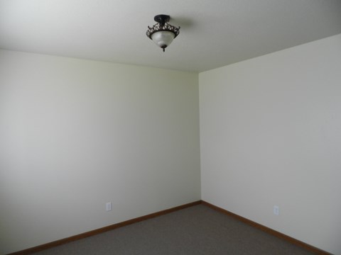 A room with a light fixture on the ceiling and two switches on the wall.