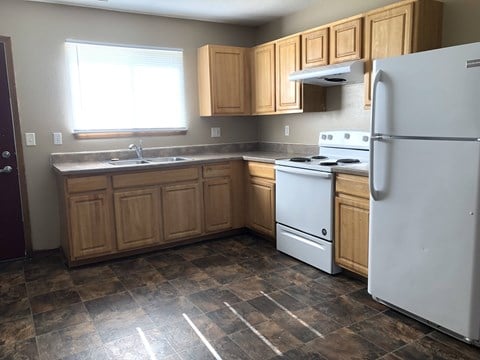 A kitchen with a white refrigerator, white stove, and wooden cabinets.