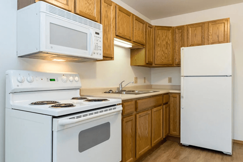 A white stove and microwave in a kitchen with wooden cabinets.