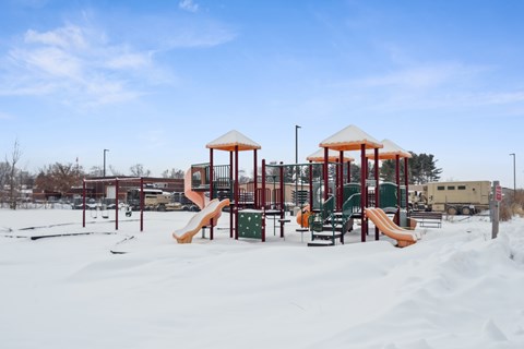 A playground with a yellow slide and a red roofed structure.