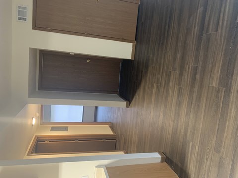 A wooden cabinet with a black object on top is mounted on a wall with wood paneling.