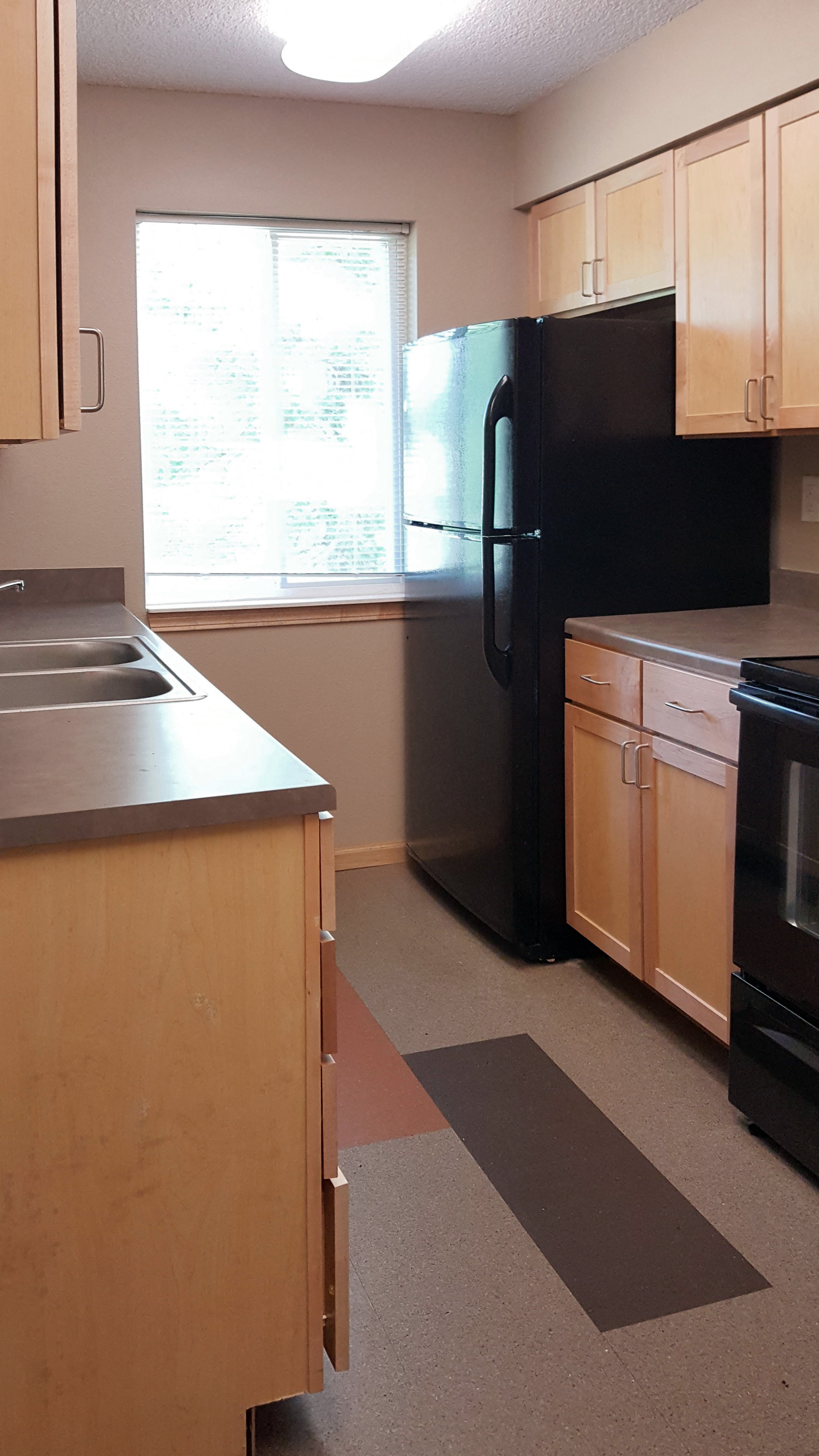 A kitchen with a black refrigerator and wooden cabinets.