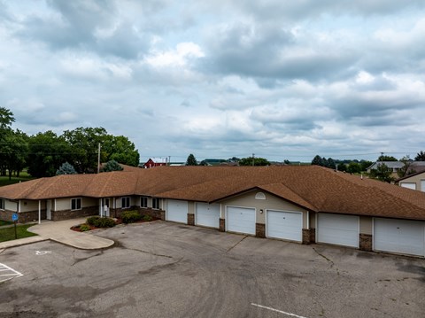 A parking lot in front of a building with a brown roof.