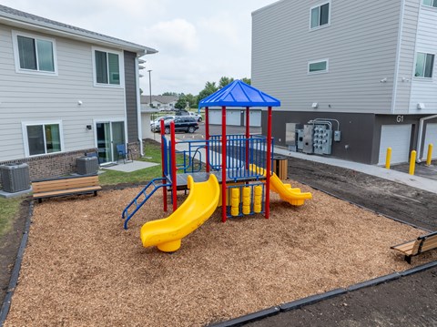 A playground with a blue and yellow slide in the foreground.