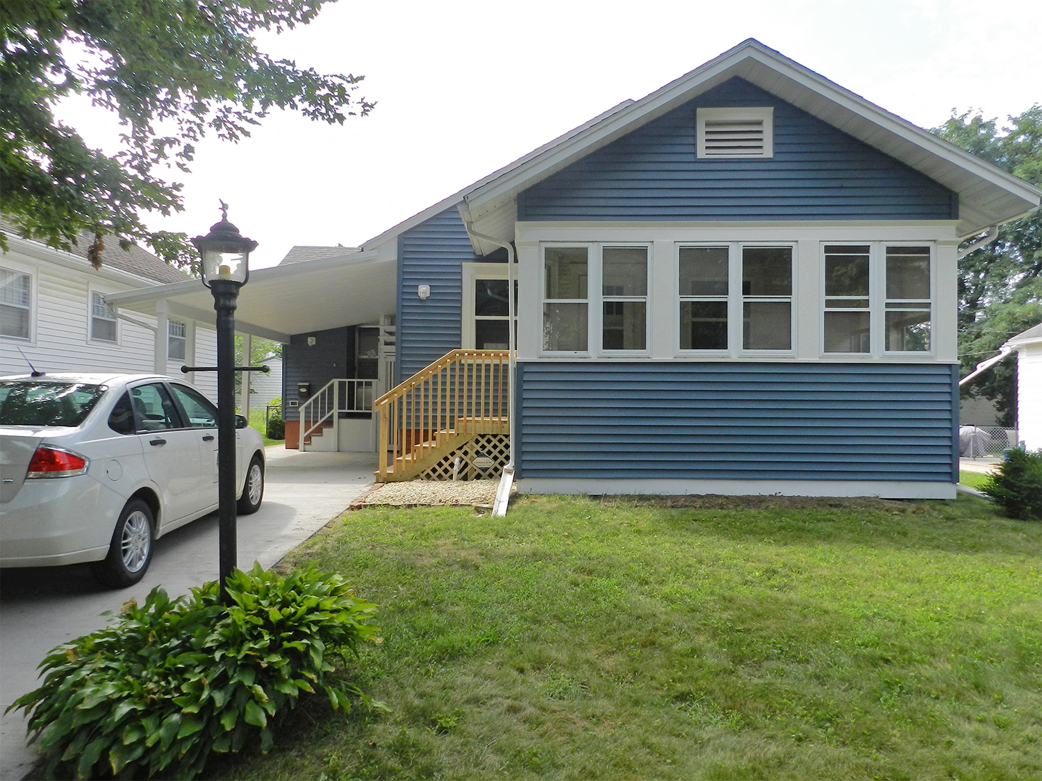 A blue house with a white car parked in front.