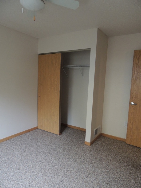 A room with a carpeted floor and a wooden door.