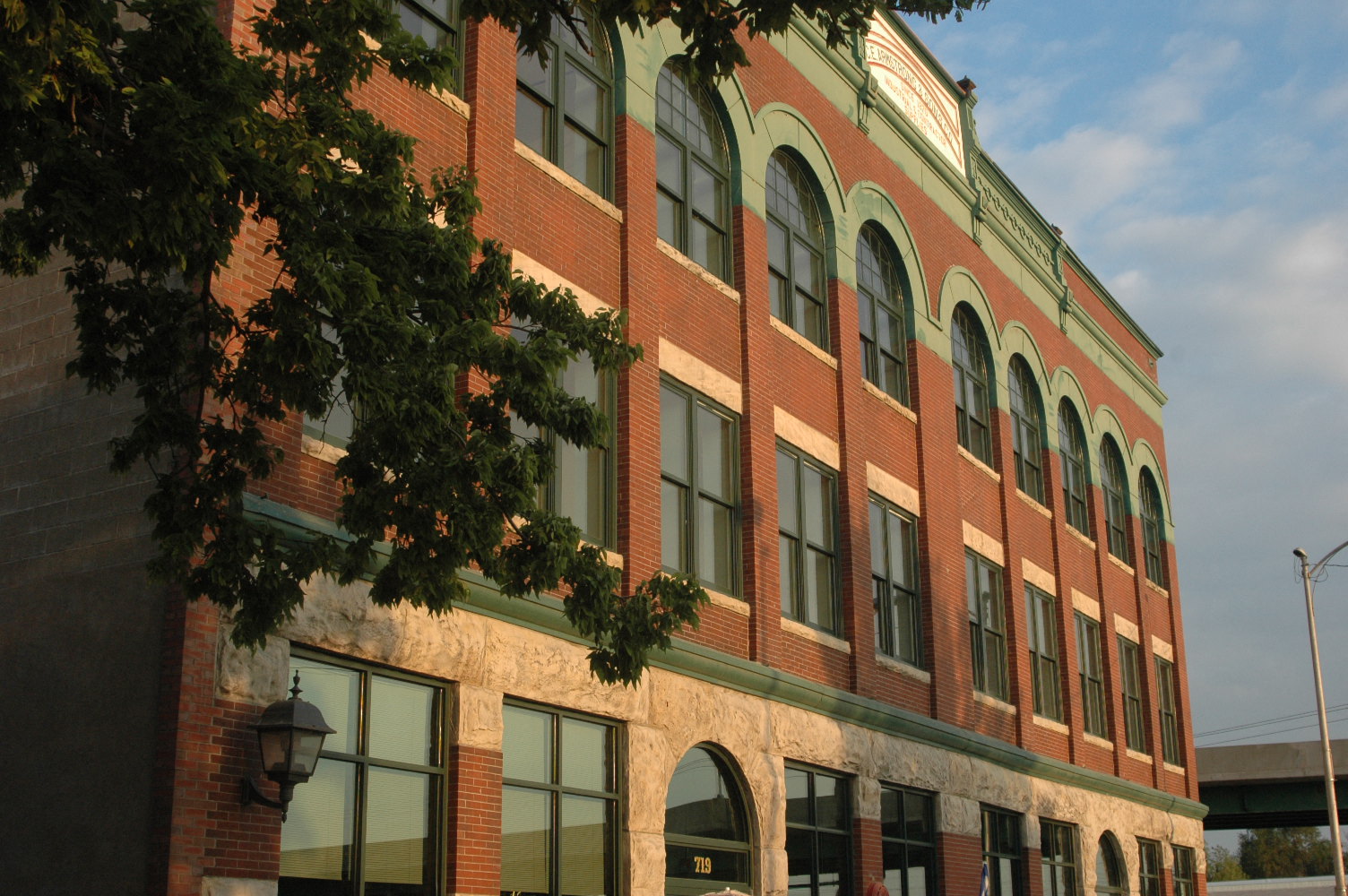 A red brick building with green trim and arched windows.