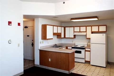 A kitchen with a white refrigerator and wooden cabinets.