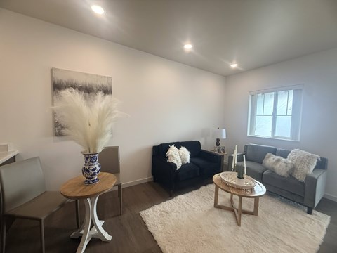 A living room with a black couch and a wooden coffee table.