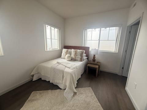 A bedroom with a bed, a small table, and a rug.
