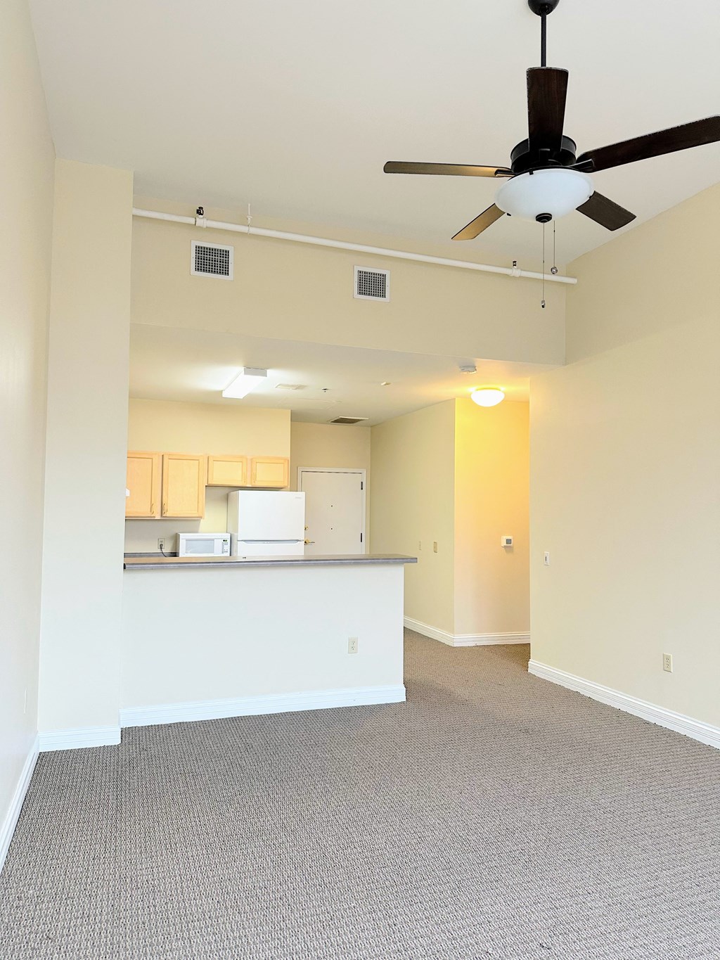 an empty living room and kitchen with a ceiling fan