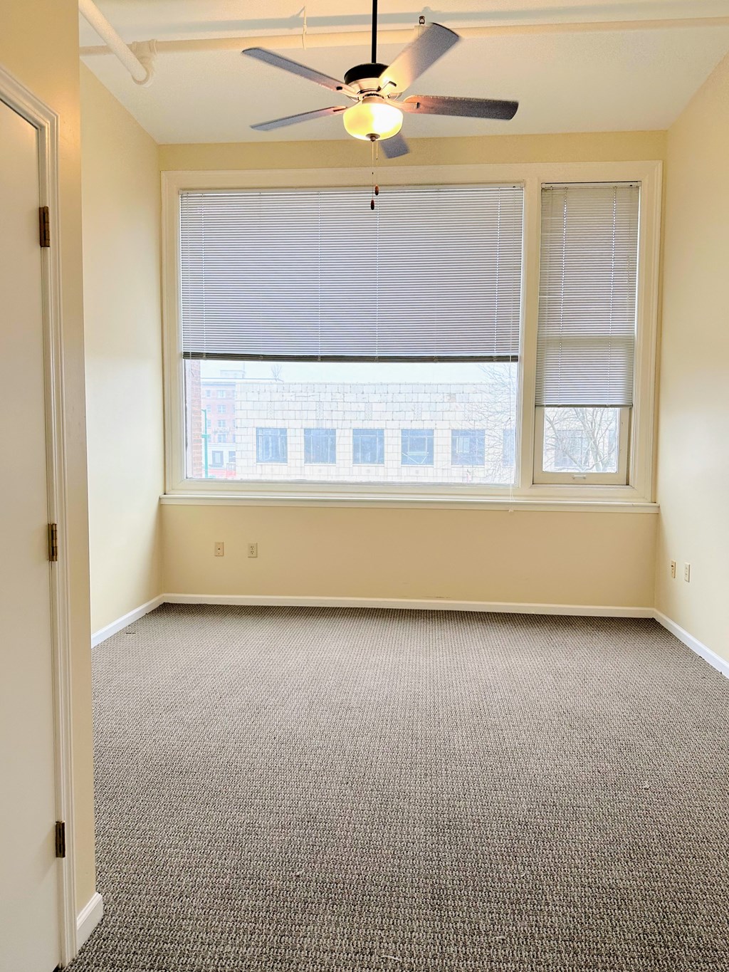 an empty room with a large window and a ceiling fan