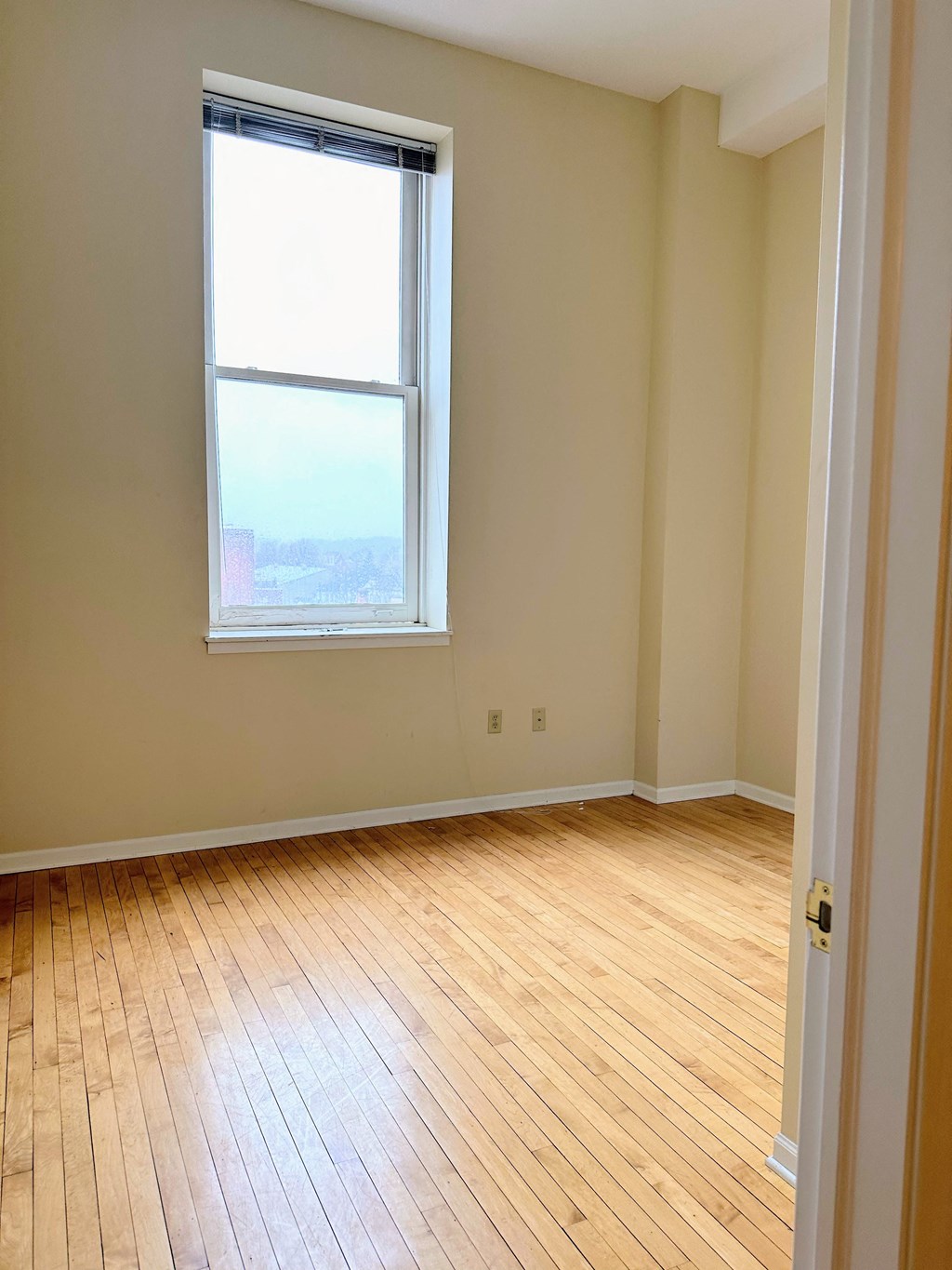 an empty room with a window and wooden floors