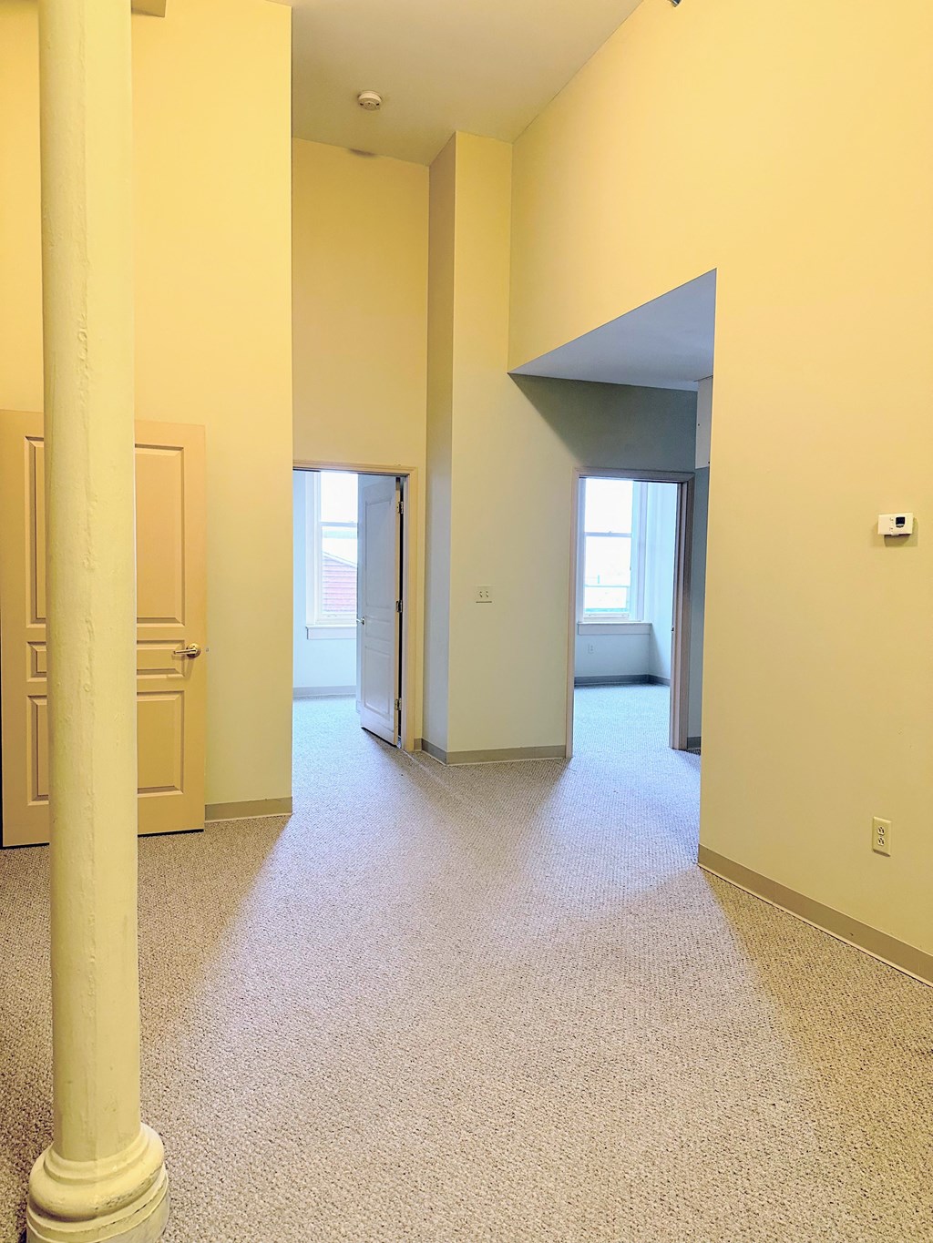 an empty living room with pillars in the middle of it