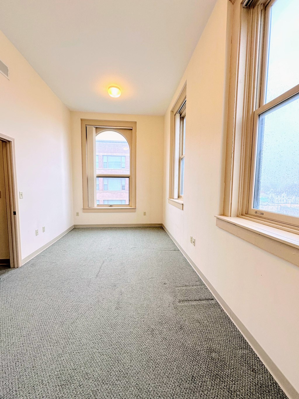 a room with a carpeted floor and two windows