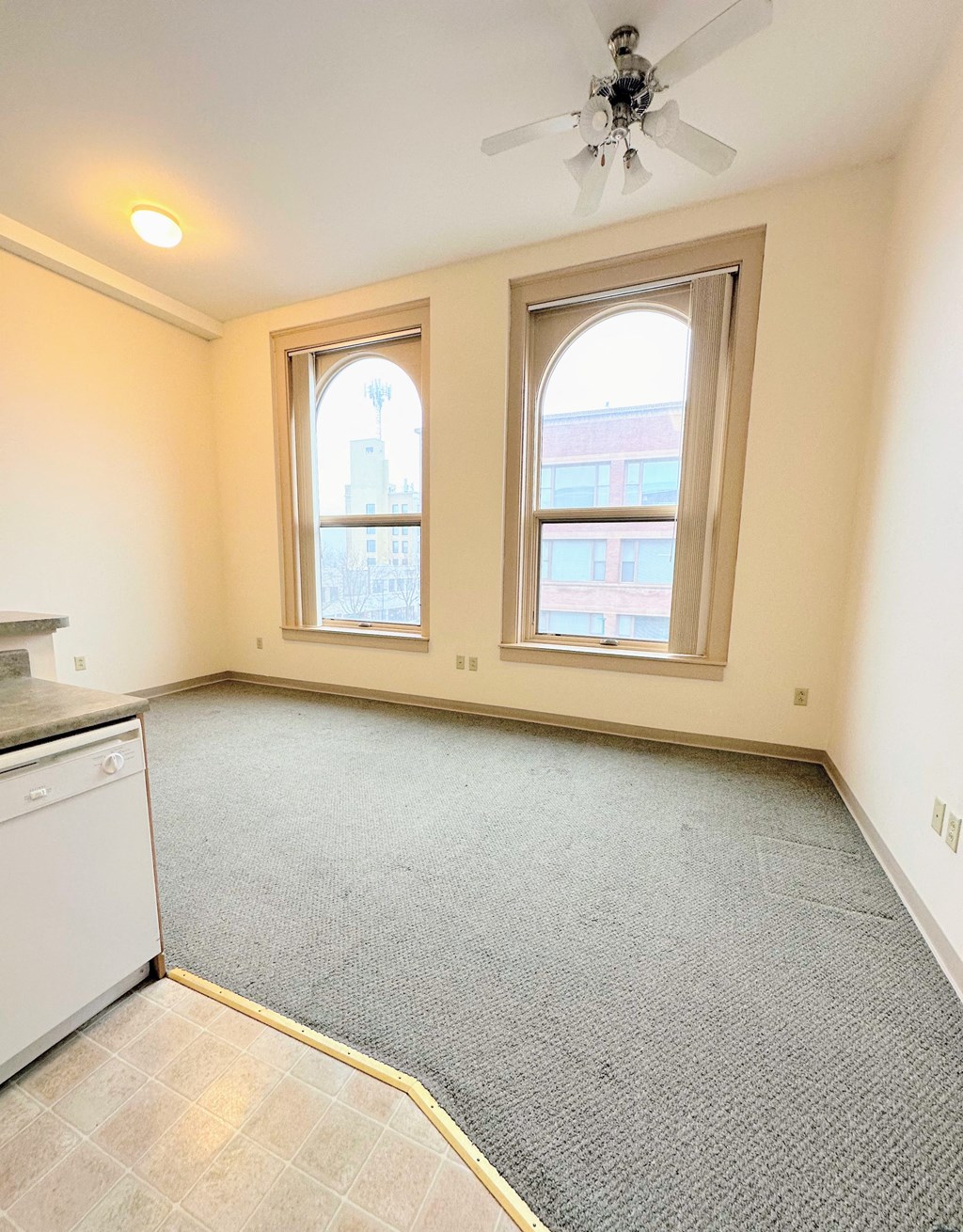 an empty kitchen with a ceiling fan and two windows