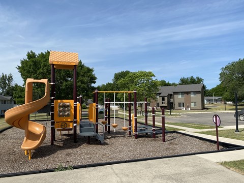 A playground with a yellow slide and swings.