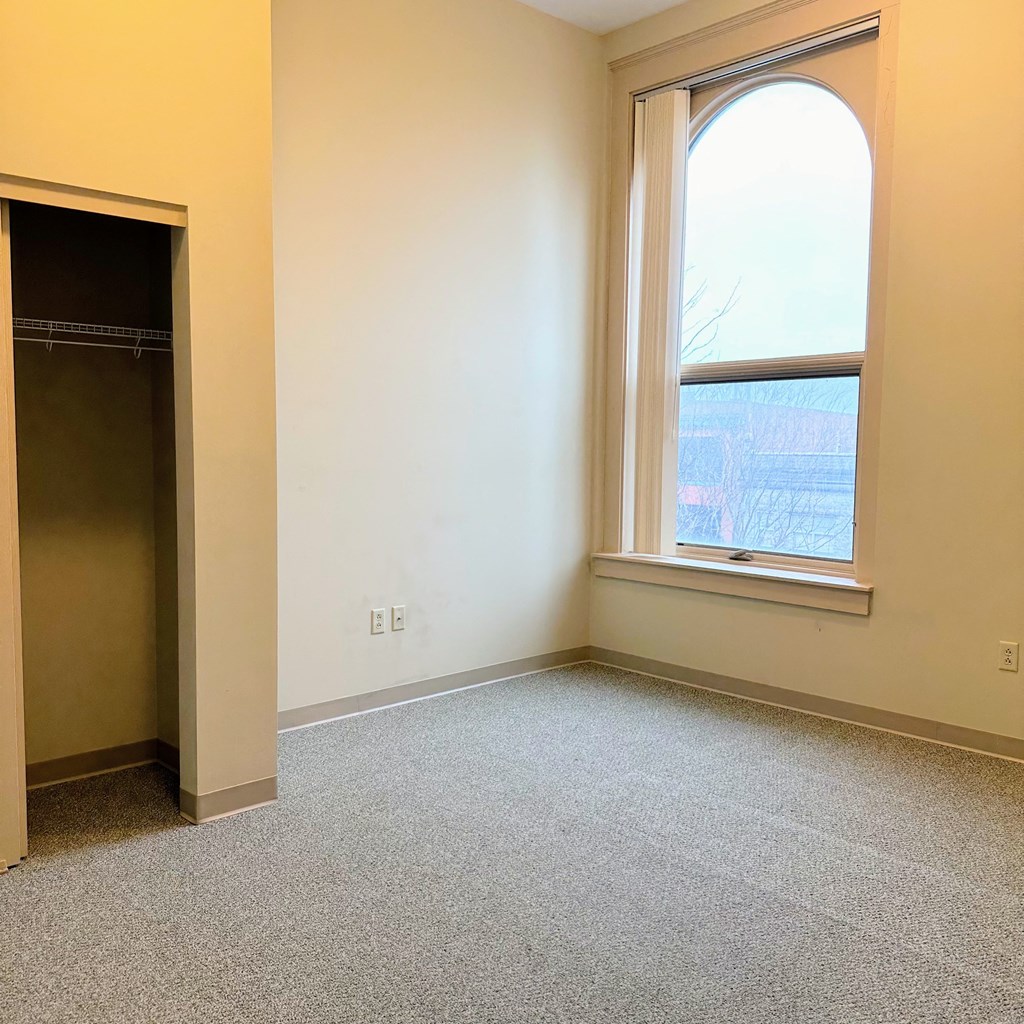 an empty room with a window and a closet